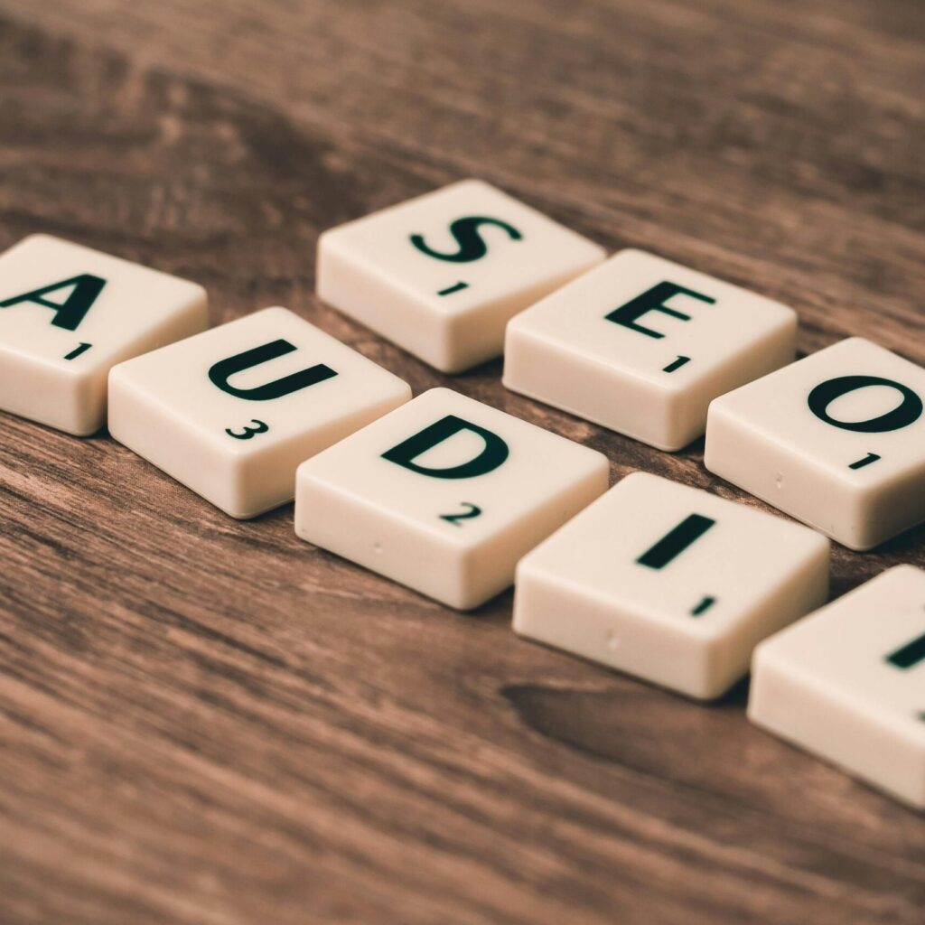 Scrabble tiles spelling SEO Audit on wooden surface, symbolizing digital marketing strategies.