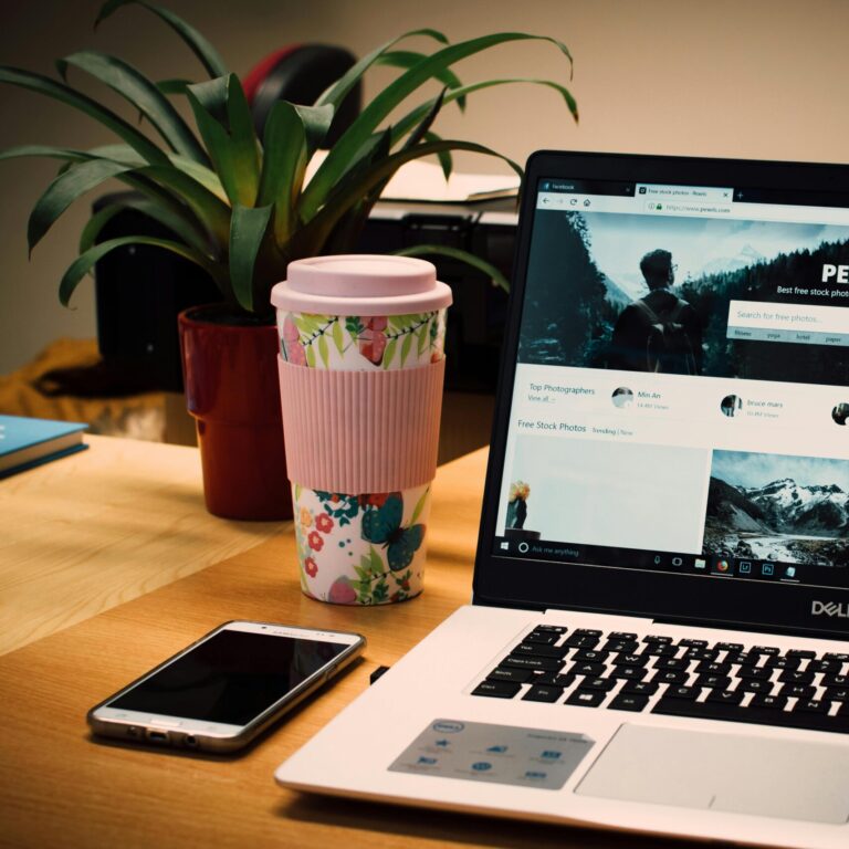 A tidy desk setting with a laptop showing a stock photo website and a smartphone.