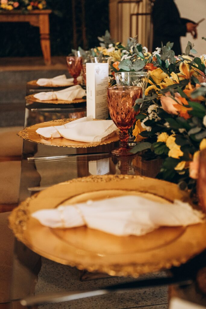 Luxurious table setting with golden plates and vibrant floral centerpiece for an elegant event.
