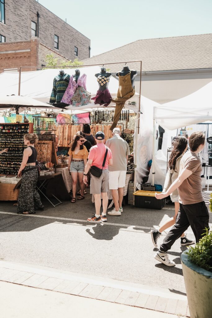 Outdoor market in Chicago with people shopping at colorful stalls under sunny skies.